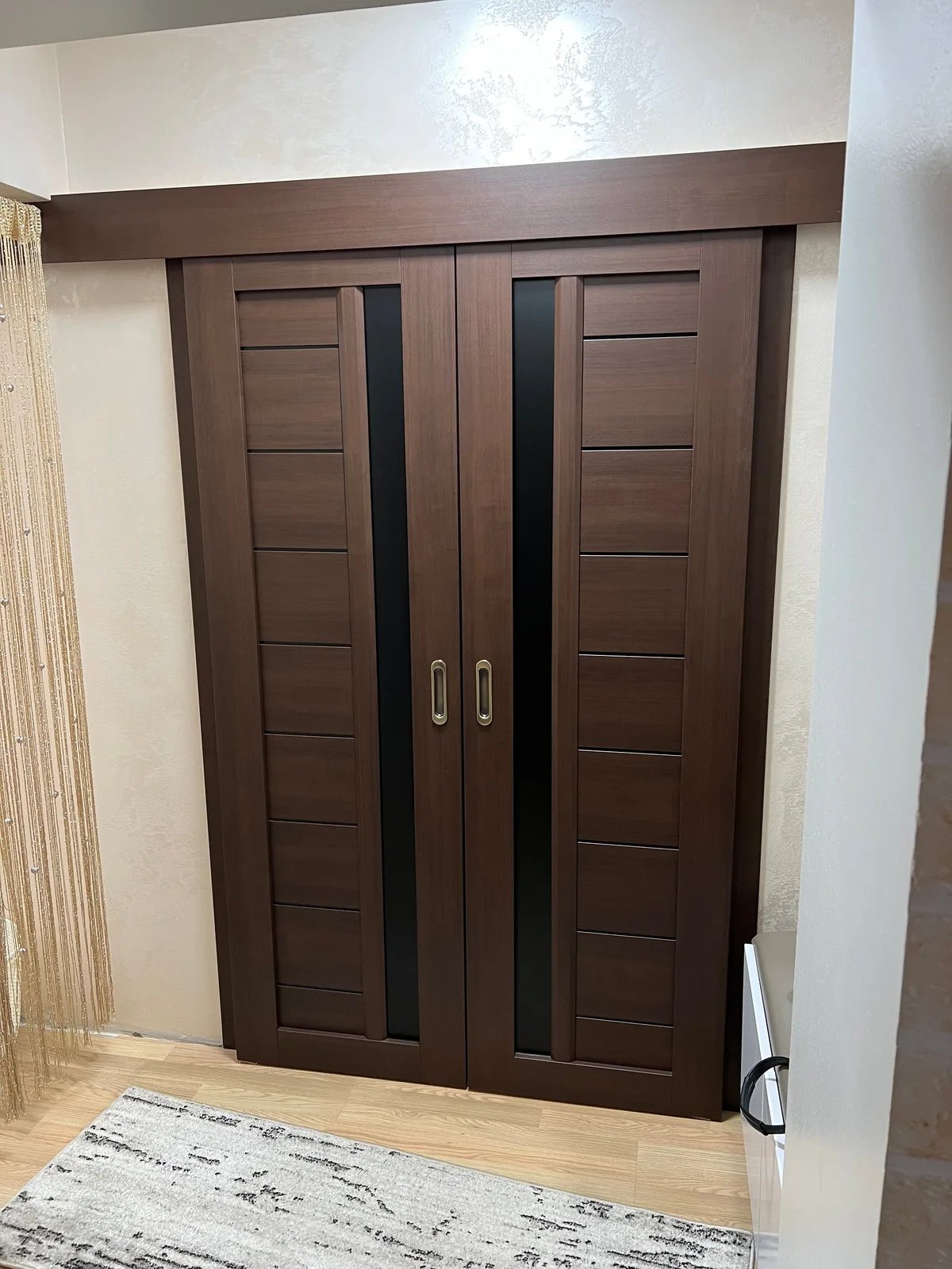 Ușă dublă de culoarea stejarului închis, cu sticlă neagră și mânere încastrate aurii